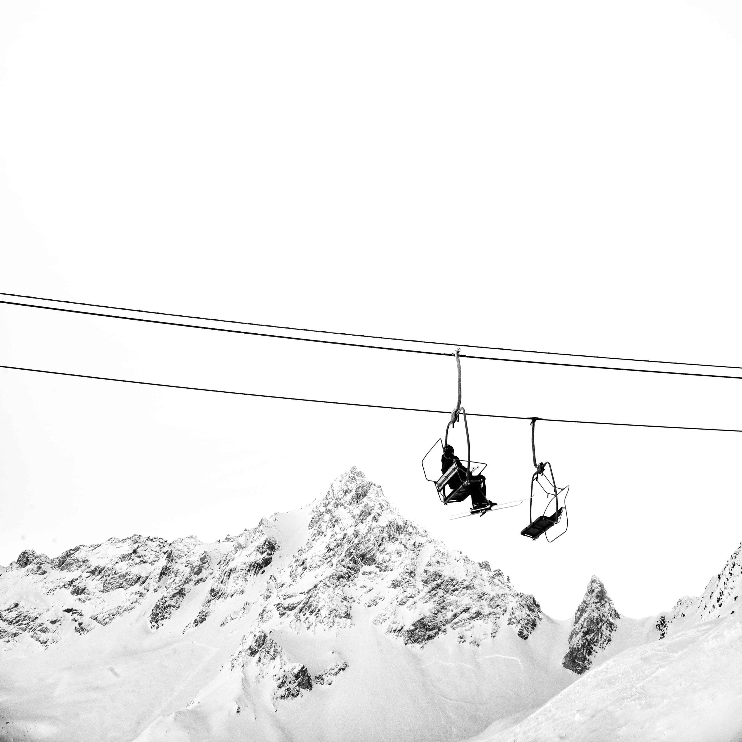 Chairlift above a snow-capped summit, black and white