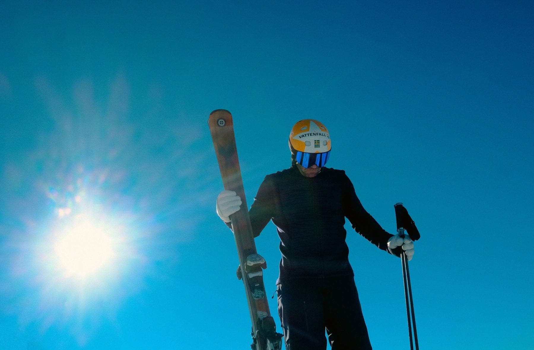 Ski instructor carrying his skis under a blue sky