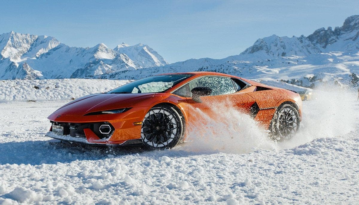 Orange sports car drifting through the snow