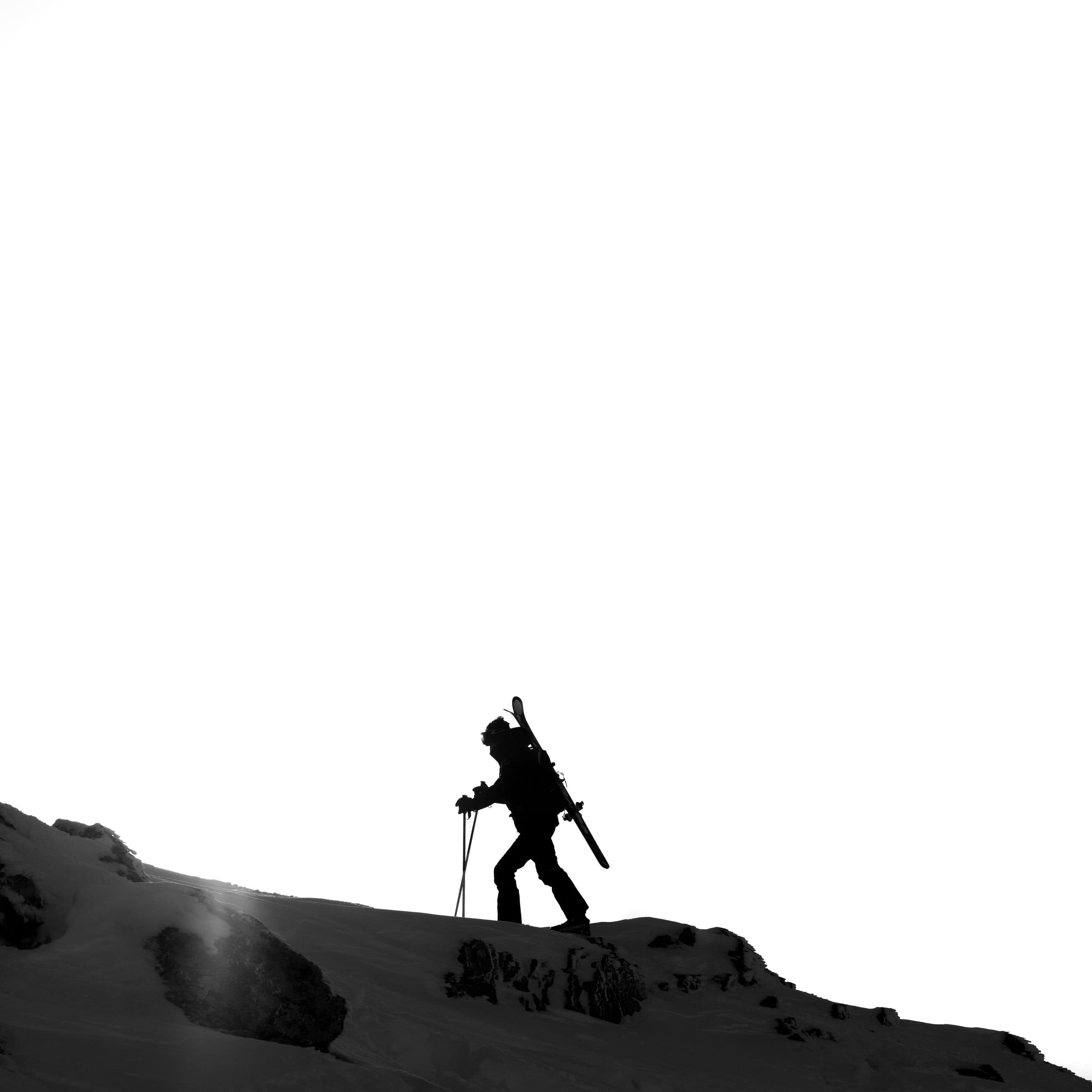 Ski tourer climbing a ridge against the light, black and white