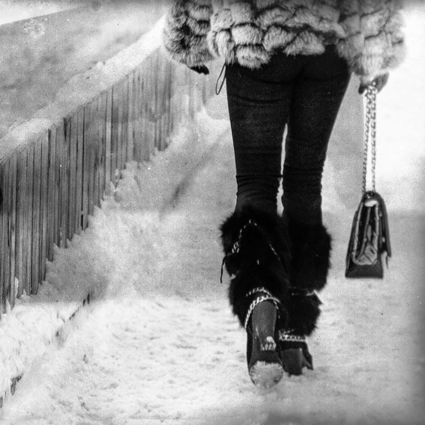 Silhouette in a fur coat walking through the snow, black and white