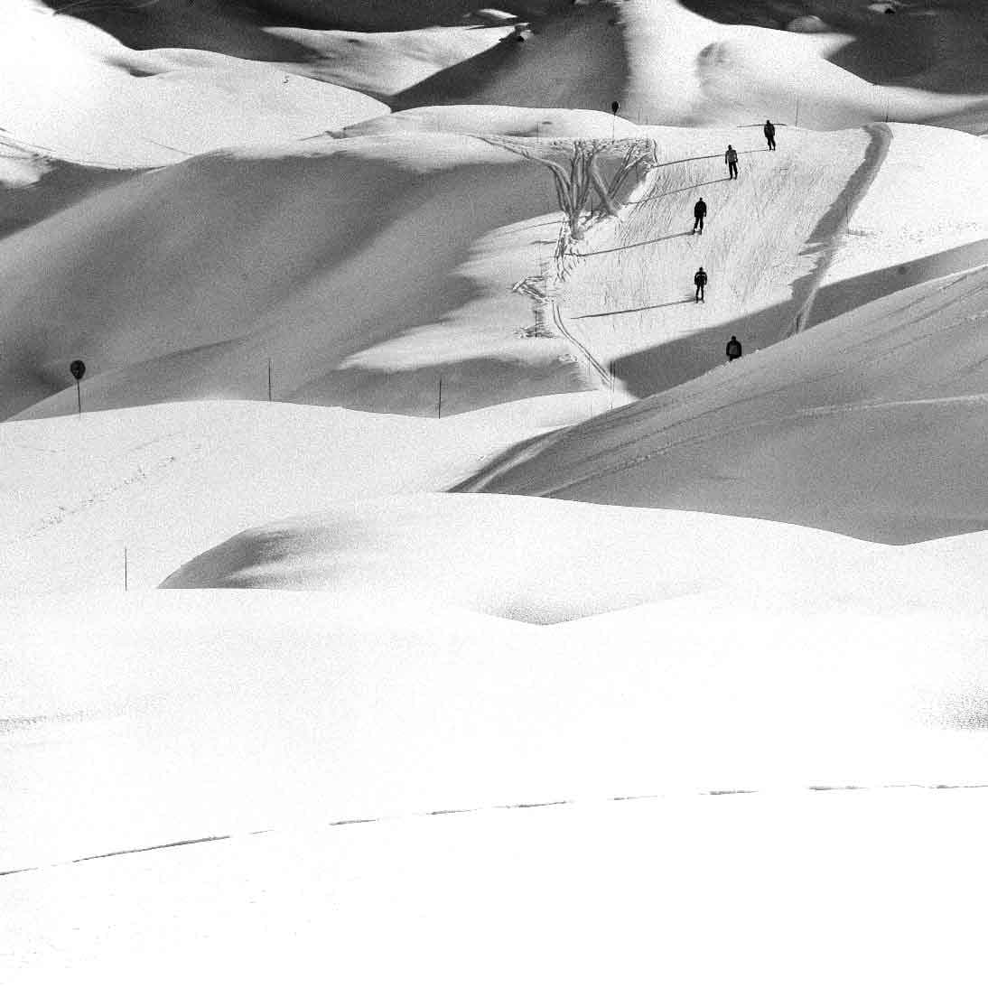 Skiers descending an untouched slope, overview of the ski area